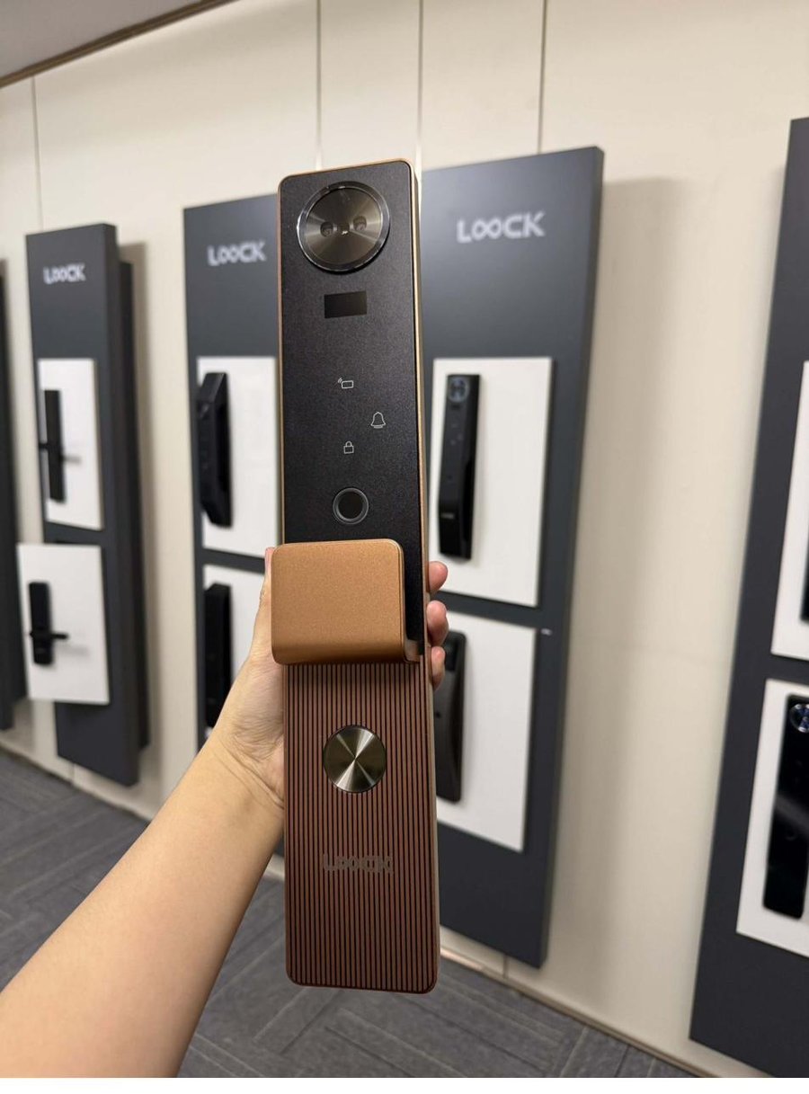 A LOOCK smart lock held up in front of a showroom wall of lock displays